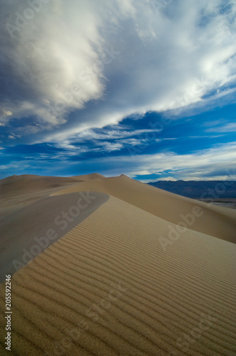 Sand dunes and a cloudy sky create a dramatic landscape.