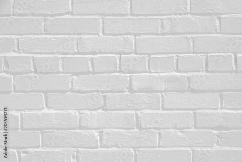 Faded white painted brick wall surface with highlights and shadows. Neutral light gray flat texture and pattern. Architectural masonry work on a building.