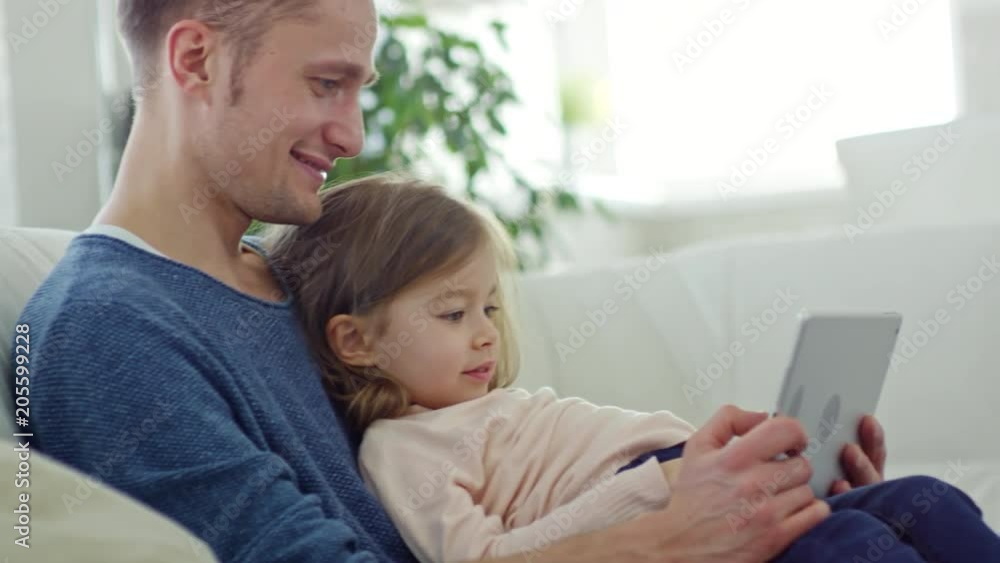 Side view of happy father and cute little daughter looking at tablet Side view of happy father and cute little daughter looking at tablet