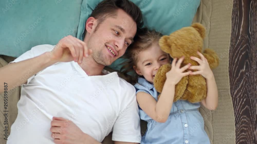 Directly above shot of cute little girl lying on floor with happy father and playing with plush toy Directly above shot of cute little girl lying on floor with happy father and playing with plush toy