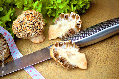 On the table, green lettuce leaves and early steppe marine fungus (Lat.Morchella steppicola) or fungus (Verpa bohemica). Ingredient. Control of excess weight. Vegetarian and diet food. photo