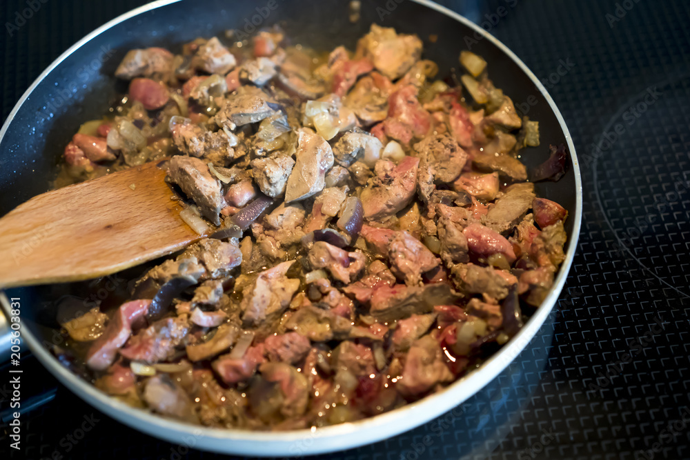 The liver with sweet onions and spices is fried in frying pan on an electric stove The liver with sweet onions and spices is fried in frying pan on an electric stove