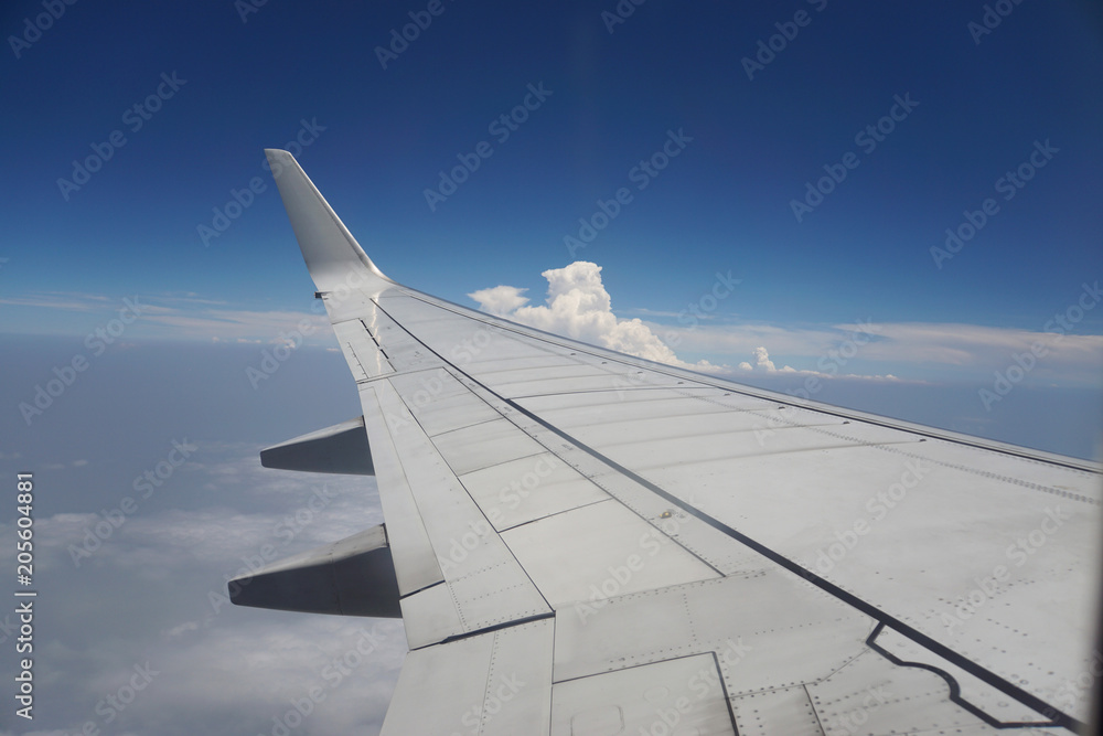 Close up airplane wing while plane in blue sky