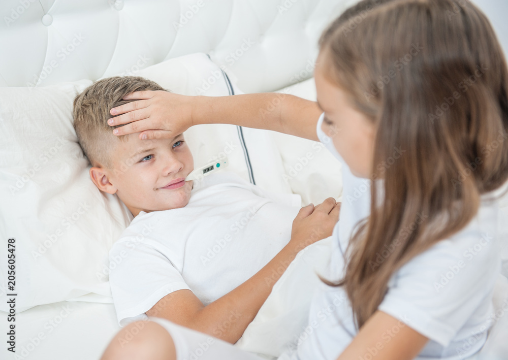 Girl touches forehead to her smiling sick brother, checking the temperature