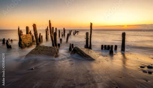 Morning sunlight hits old wooden posts on the beach at Spurn Point near Hull, Yorkshire, England.