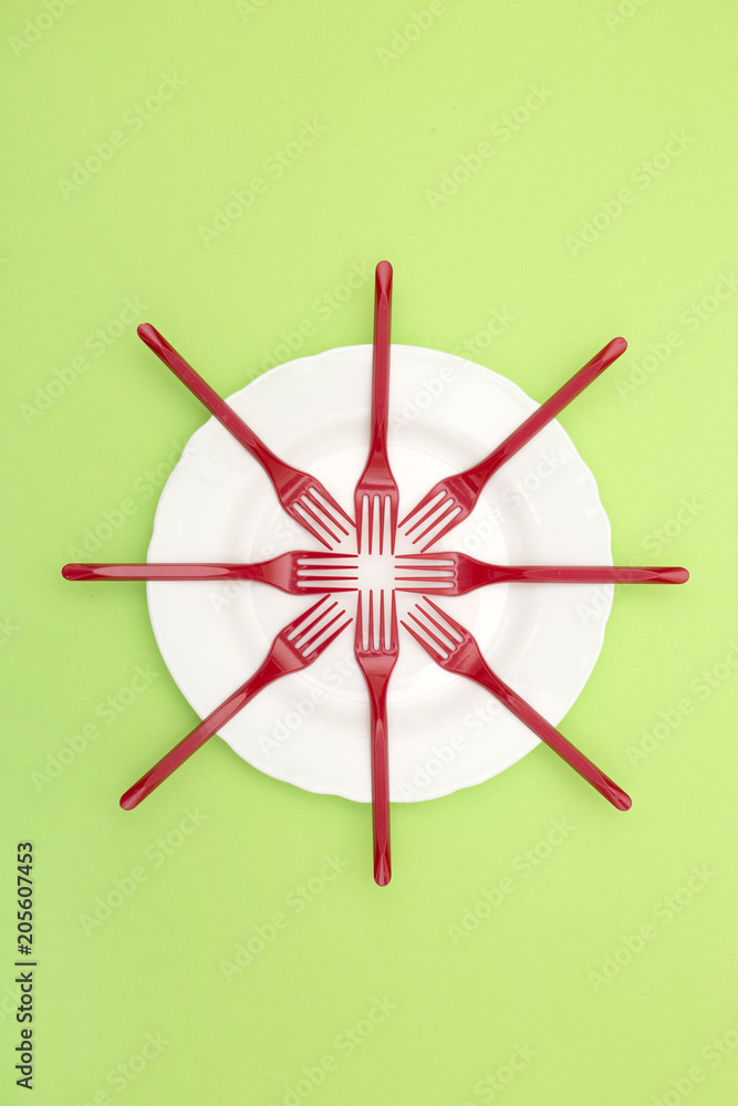 Still Life with plastic forks and a plate on a green background, for decoration, for text design, for template Still Life with plastic forks and a plate on a green background, for decoration, for text design, for template