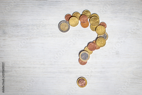 Symbol of question mark made of euro coins on the white wooden background