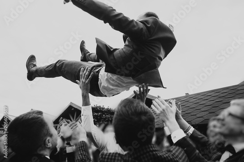 Foto men tossing up groom at stylish wedding reception