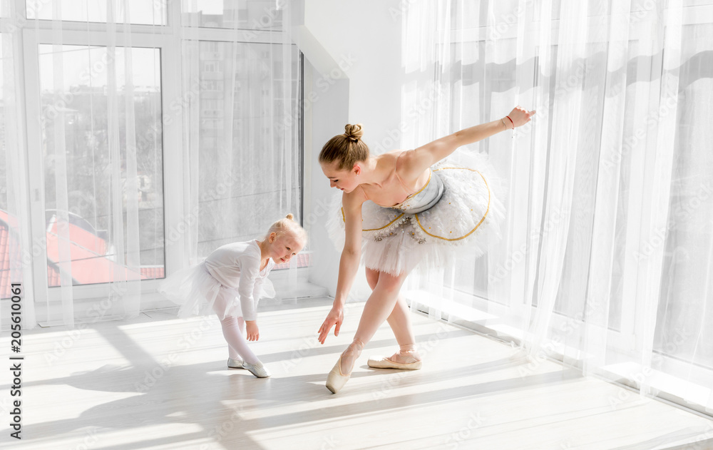 Obraz premium Young gorgeous ballerina with her little daughter dancing in studio