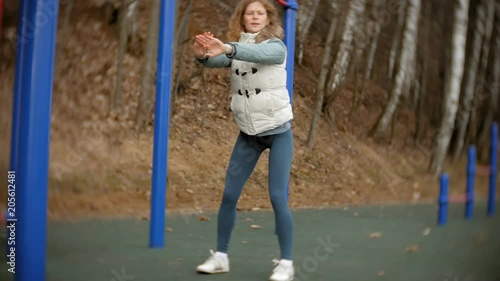 young fitness woman doing exercises on the gym in an outdoor park photo