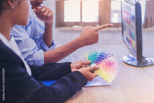 group of designer working graphic on computer with color chart and write short note for choose a color