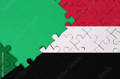 Sudan flag  is depicted on a completed jigsaw puzzle with free green copy space on the left side photo