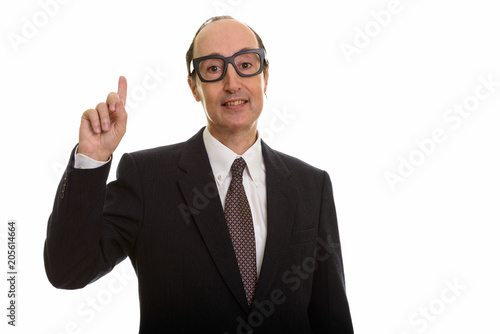 Studio shot of happy mature businessman smiling while pointing f