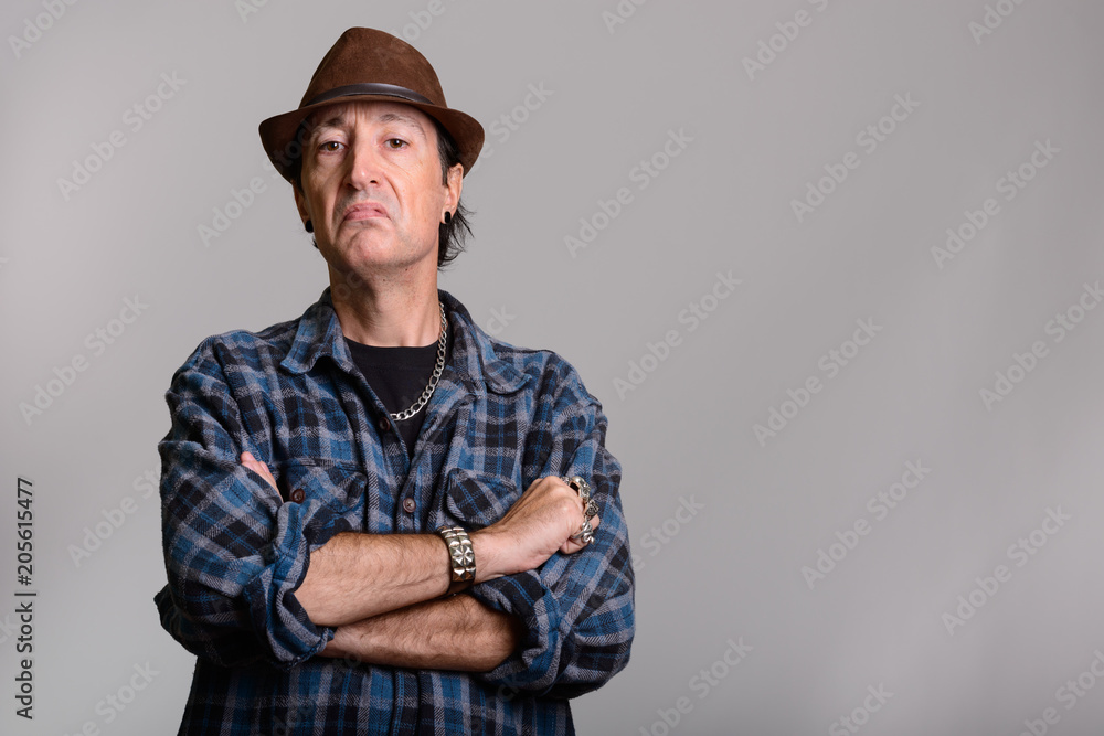 Studio shot of angry mature gangster man with arms crossed Studio shot of angry mature gangster man with arms crossed