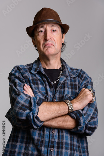Studio shot of angry mature gangster man with arms crossed