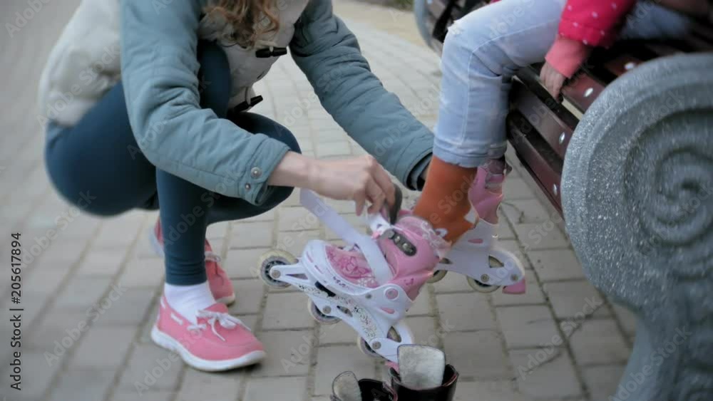 Mom and daughter ride on roller skates. Girl learning to roller skate, and falls. Mom teaches daughter to ride on rollers Mom and daughter ride on roller skates. Girl learning to roller skate, and falls. Mom teaches daughter to ride on rollers