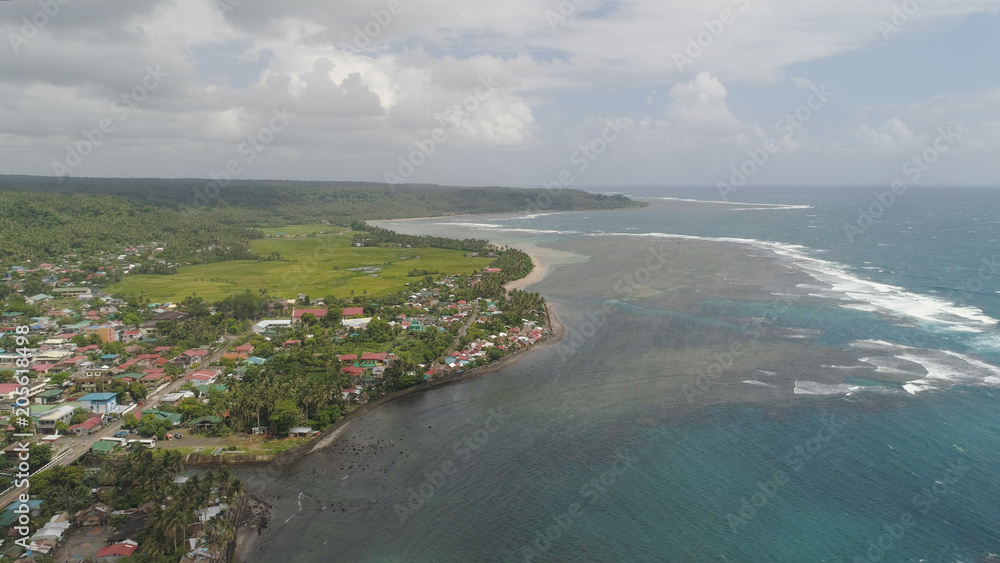 Aerial view of seashore with coastal town, beach, lagoons and coral reefs. Bulusan, Philippines, Luzon. Ocean coastline with turquoise water. Tropical landscape in Asia.