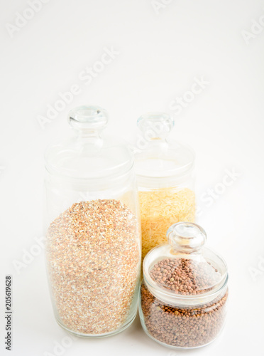 three transparent containers with a grain of rice, buckwheat and lentils