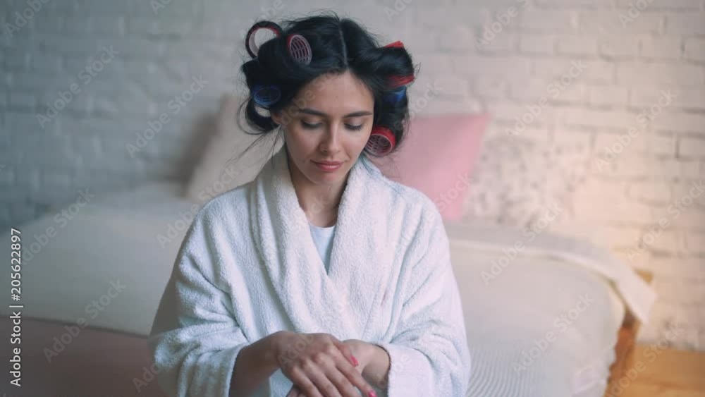 A young girl, a housewife in curlers, caring for the skin of the hands. Beauty Spa woman portrait with perfect skin. beautiful brunette