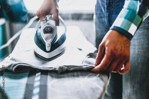 Fototapeta Man at home ironing clothes