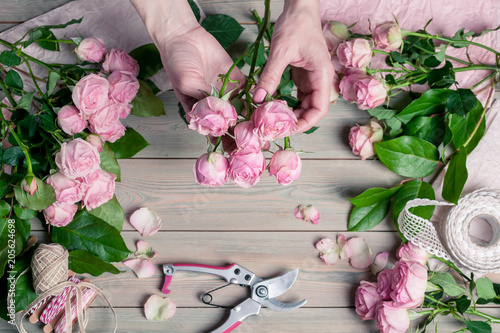 Florist at work. Elegant female hands collect a wedding bouquet of pink roses. People in the process of work © yusev