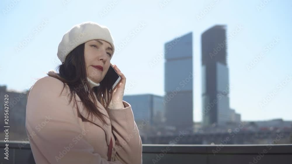 Woman in coat with phone against a background of high buildings of a megacity. Woman in coat with phone against a background of high buildings of a megacity.