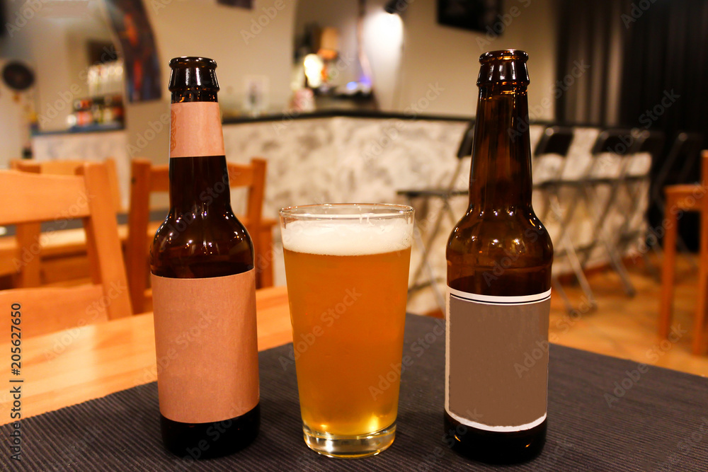 Two beer bottles and full glass of light beer in a cozy craft beer bar