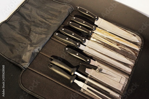 A set of professional kitchen knives on a black table..