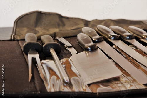 A set of professional kitchen knives on a black table..