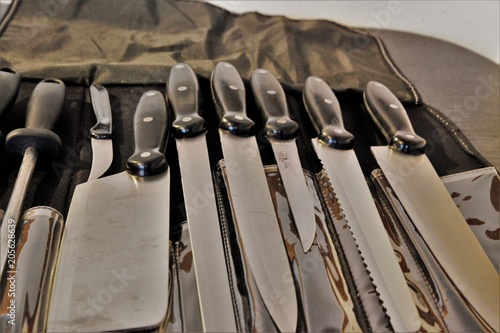 A set of professional kitchen knives on a black table..