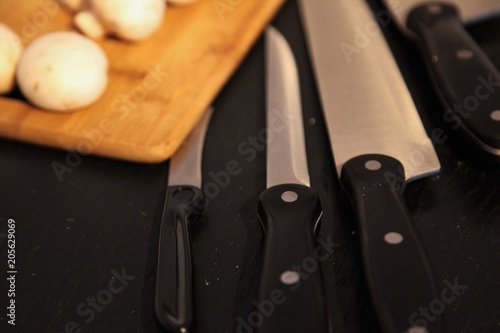 A set of professional kitchen knives on a black table..