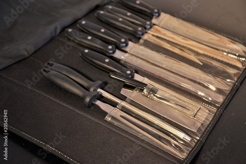 A set of professional kitchen knives on a black table..