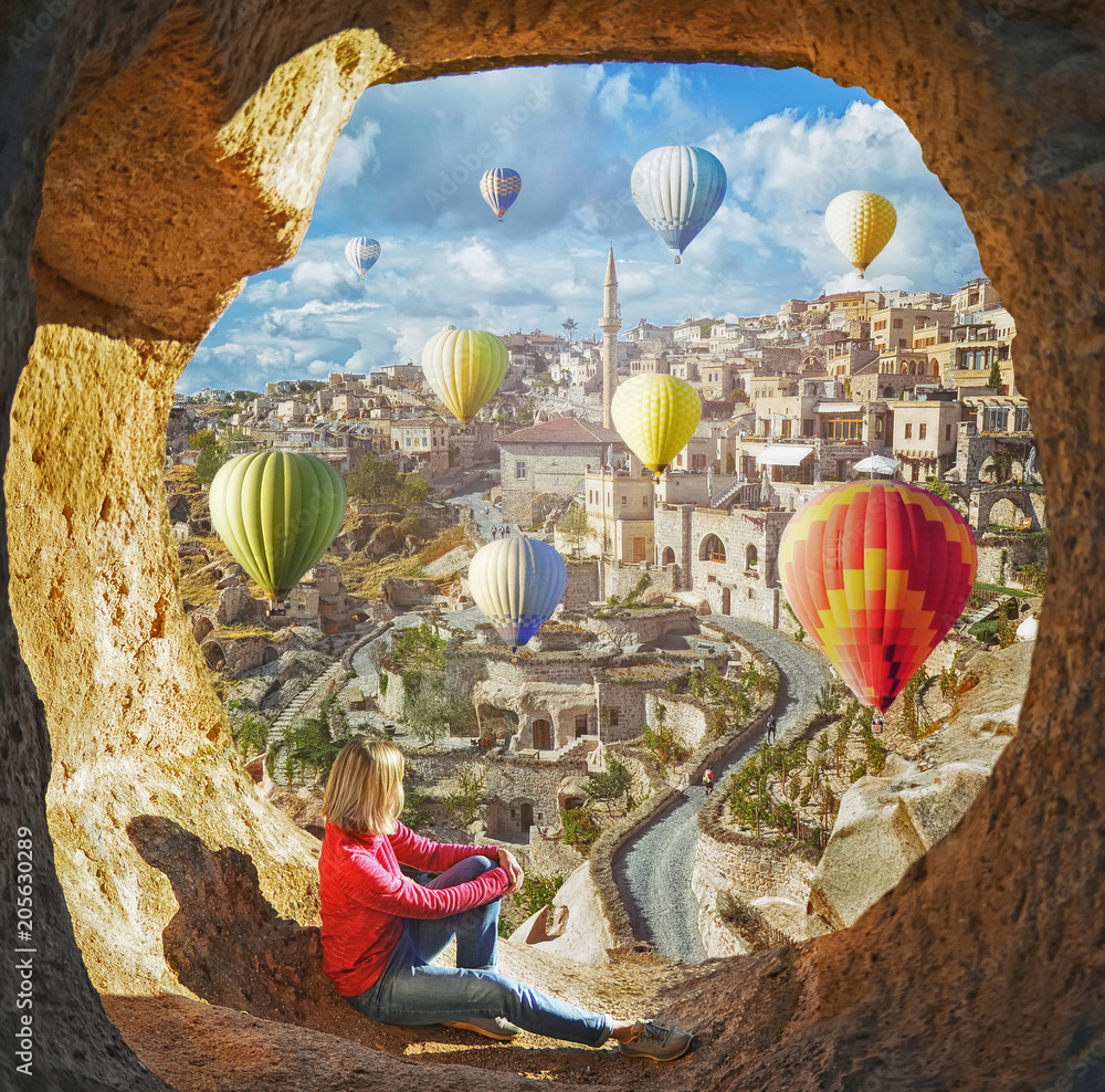 Obraz premium Woman watching like colorful hot air balloons flying over the valley at Cappadocia, Turkey. Volcanic mountains in Goreme national park.