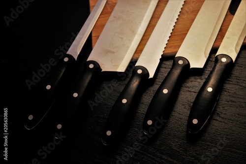 A set of professional kitchen knives on a black table..