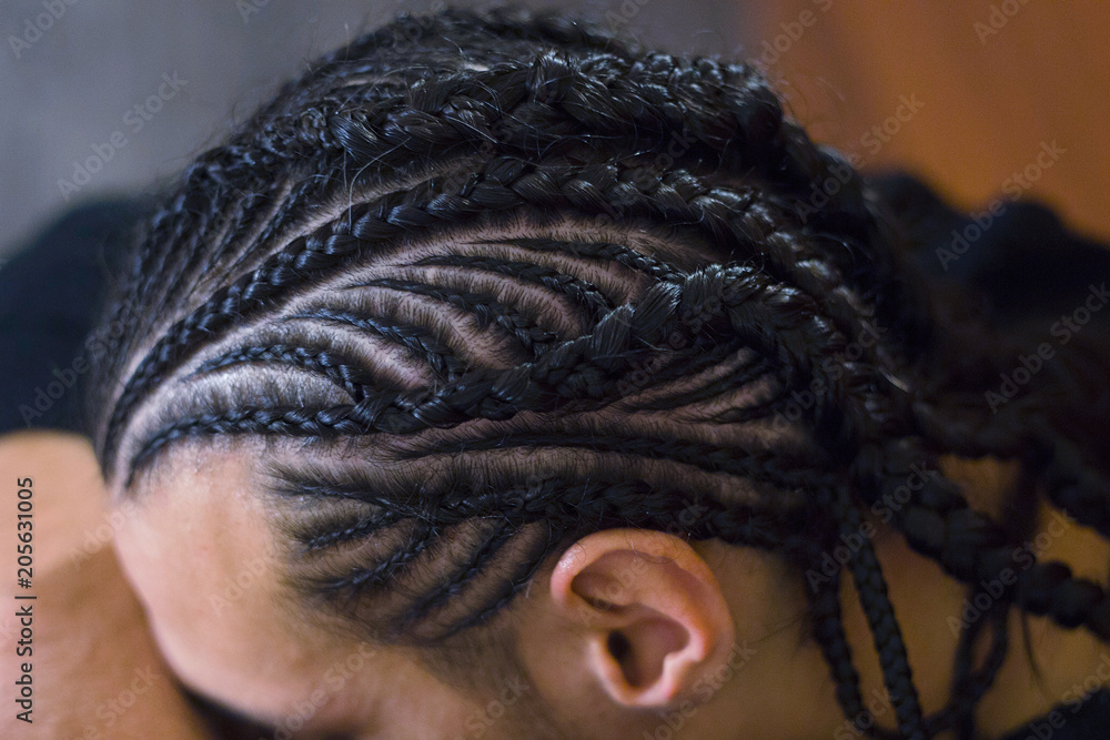 thin braids braided on the head of a man, photo close-up for a background