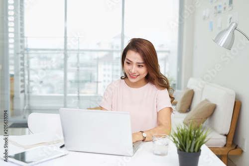 Young pretty Vietnamese woman working with laptop in office
