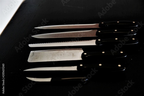 A set of professional kitchen knives on a black table..