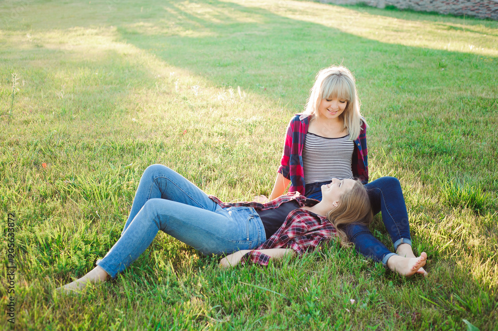 Two happy female friends playing and having fun in green grass Two happy female friends playing and having fun in green grass