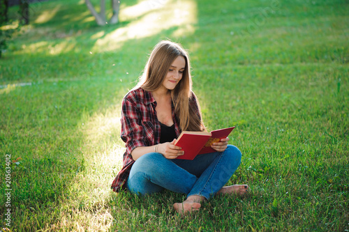 pretty blond young woman reading a book at park