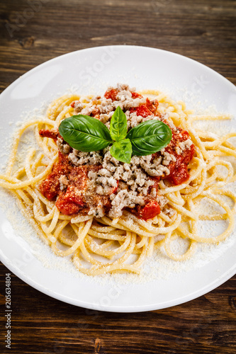Pasta with meat and tomato sauce on wooden table