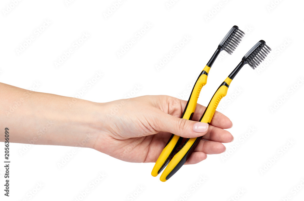 Black and yellow soft toothbrush with hand isolated on white background