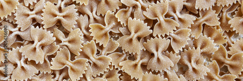 Panoramic background with spilled whole-wheat pasta bows