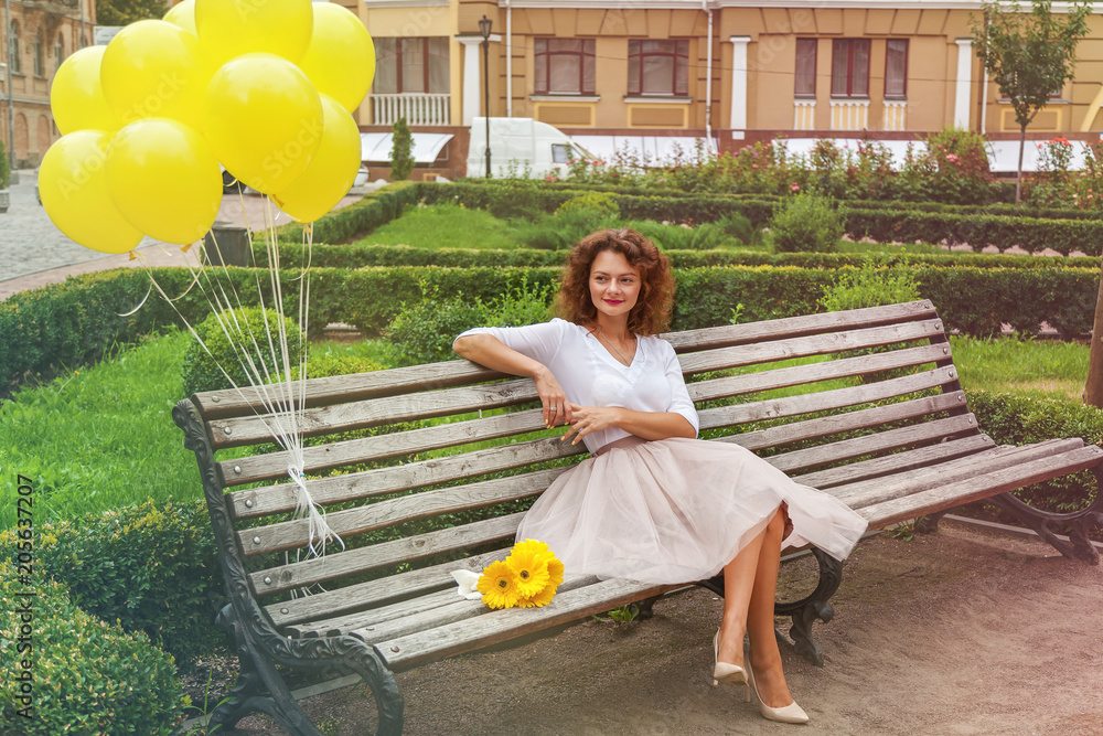 the girl is sitting on the bench in the park