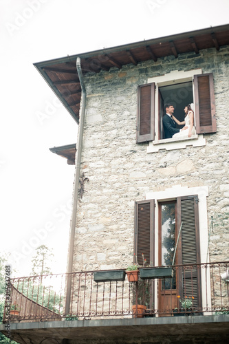 wedding couple looks out the window of a big house