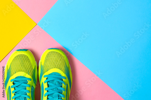 Fototapeta Naklejka Na Ścianę i Meble -  Pair of sport shoes on colorful background. New sneakers on pink, blue and yellow background, copy space. Overhead shot of running shoes. Top view, flat lay