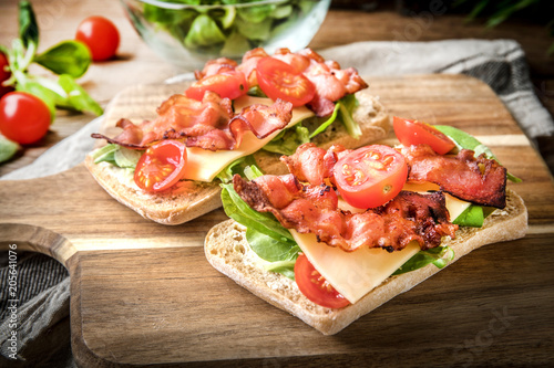 Ciabatta sandwich with arugula salad  bacon and yellow cheese.