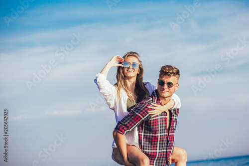 Happy couple in love on beach summer vacations. Joyful girl piggybacking on young boyfriend  having fun. © Mediteraneo