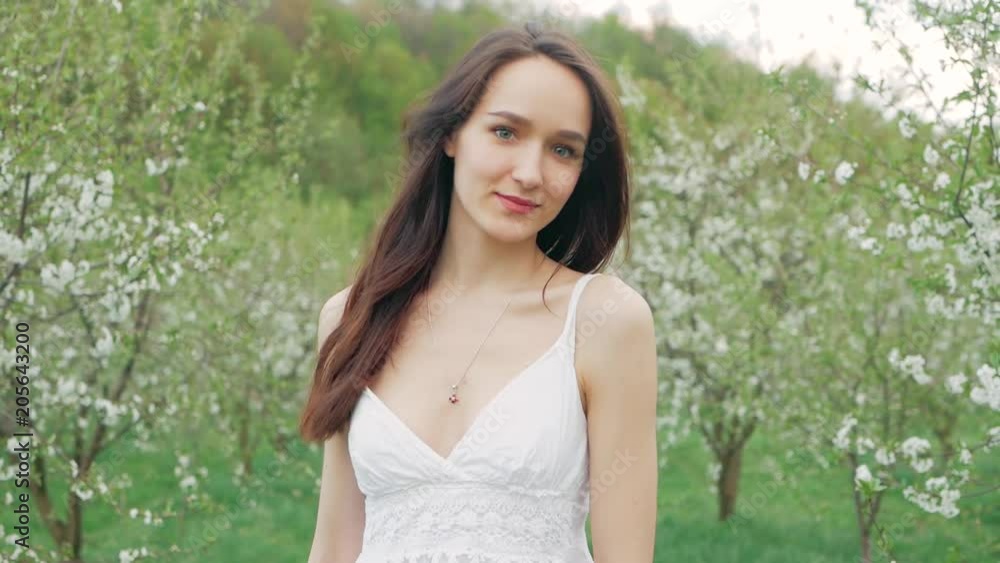 spring fashion portrait of a beautiful happy young woman in white dress with long brown hair run and enjoy smell flowers in the blossoming garden spring fashion portrait of a beautiful happy young woman in white dress with long brown hair run and enjoy smell flowers in the blossoming garden