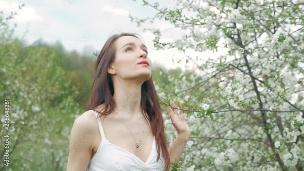 spring fashion portrait of a beautiful happy young woman in white dress with long brown hair run and enjoy smell flowers in the blossoming garden spring fashion portrait of a beautiful happy young woman in white dress with long brown hair run and enjoy smell flowers in the blossoming garden