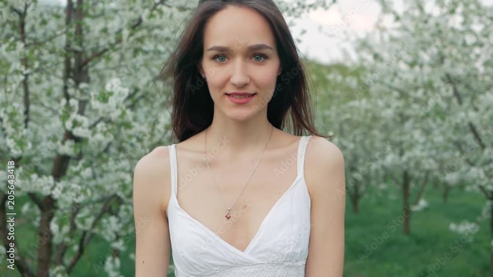 spring fashion portrait of a beautiful happy young woman in white dress with long brown hair run and enjoy smell flowers in the blossoming garden spring fashion portrait of a beautiful happy young woman in white dress with long brown hair run and enjoy smell flowers in the blossoming garden